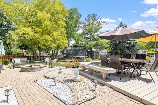 1267 Churchill Rd, Bartlett, IL 60103 - fenced backyard featuring a fire pit, a storage shed, a trampoline, outdoor dining space, and a patio area