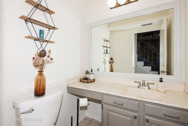 half bathroom with visible vents, tile patterned flooring, vanity, and toilet