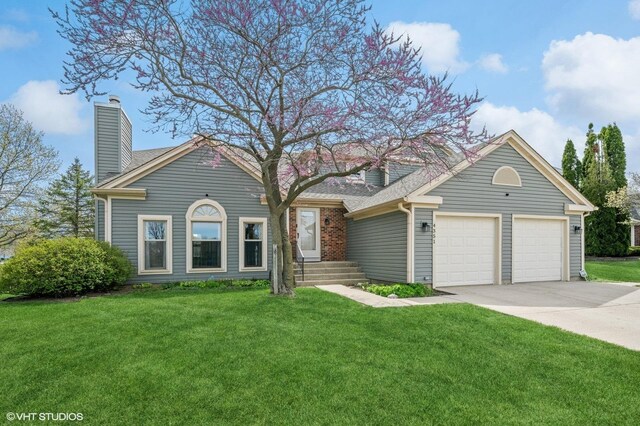 view of front facade featuring an attached garage, driveway, a chimney, and a front lawn