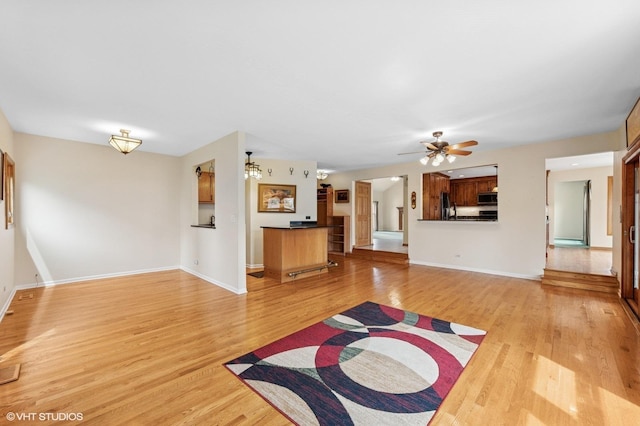 unfurnished living room with a ceiling fan, baseboards, visible vents, and light wood-style flooring