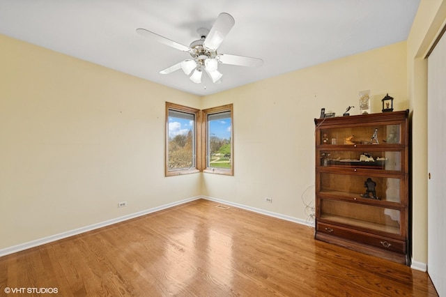 empty room with baseboards, a ceiling fan, and wood finished floors