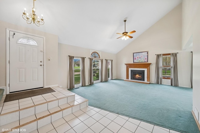 carpeted foyer with tile patterned flooring, high vaulted ceiling, ceiling fan with notable chandelier, baseboards, and a lit fireplace
