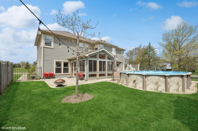 back of property featuring a yard, a fire pit, a fenced backyard, and a sunroom