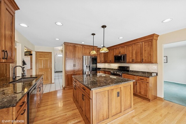 kitchen featuring a kitchen island, appliances with stainless steel finishes, brown cabinetry, and light wood-style floors