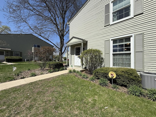 doorway to property featuring a lawn and central AC unit