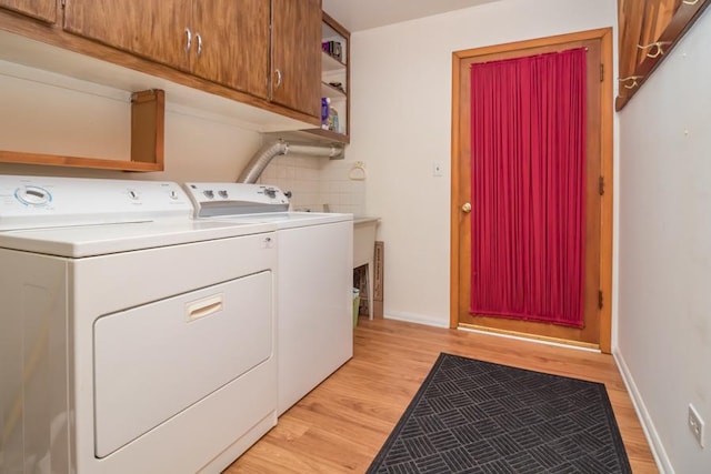 washroom with separate washer and dryer, cabinet space, baseboards, and light wood-style floors