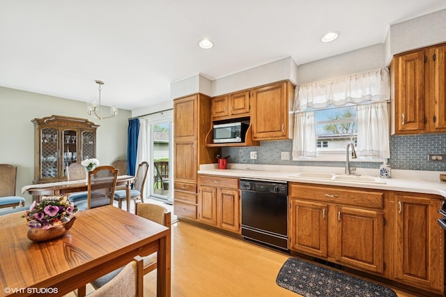 kitchen featuring black dishwasher, stainless steel microwave, brown cabinetry, and a sink