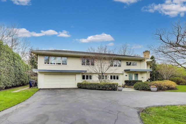view of front of house with a garage, a chimney, and driveway
