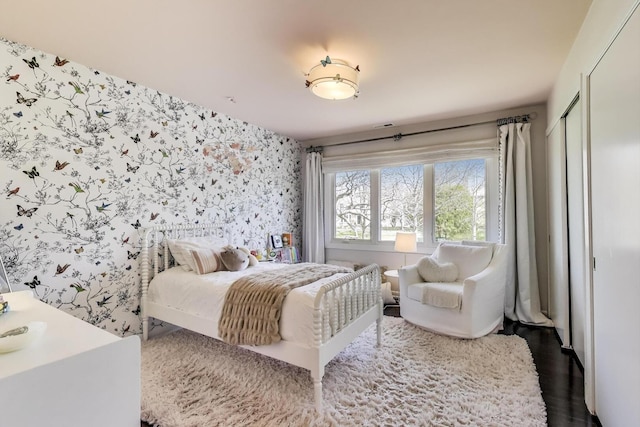 bedroom with dark wood-style flooring and wallpapered walls