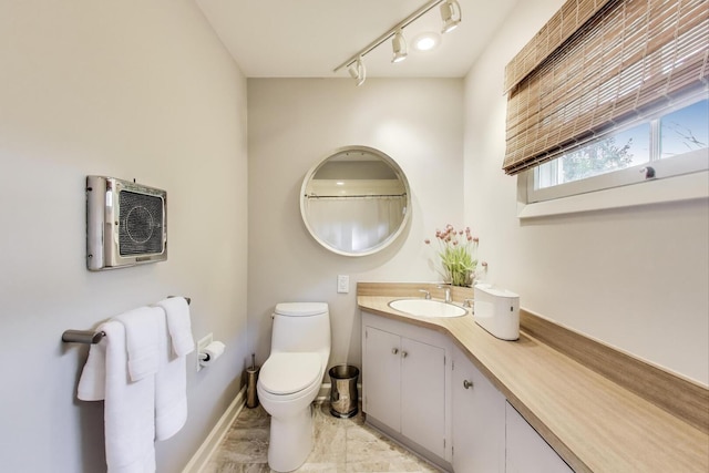 full bathroom featuring vanity, rail lighting, baseboards, and toilet