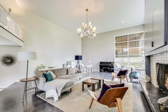 living area featuring a high ceiling, a fireplace, a chandelier, baseboards, and wood finished floors
