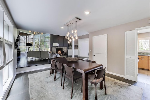 dining space featuring baseboards, a brick fireplace, recessed lighting, and a chandelier