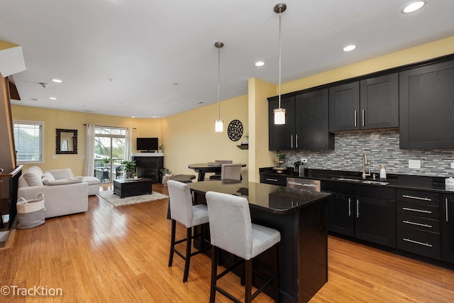 kitchen featuring a sink, dark cabinets, a breakfast bar, and light wood finished floors