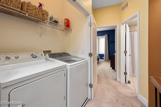 washroom with visible vents, laundry area, light carpet, baseboards, and washing machine and clothes dryer