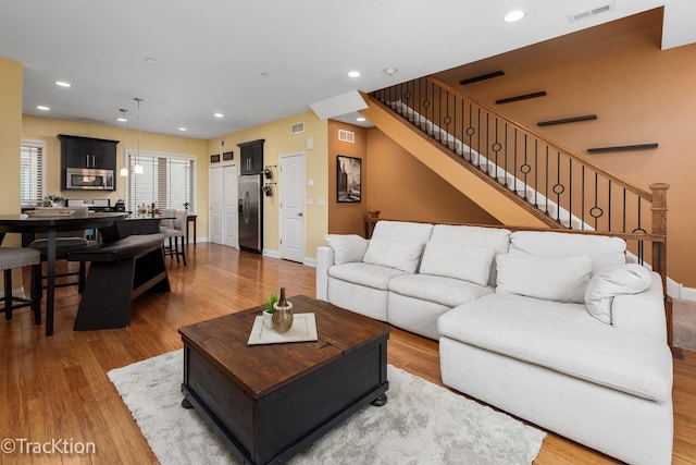 living room featuring stairway, wood finished floors, and visible vents