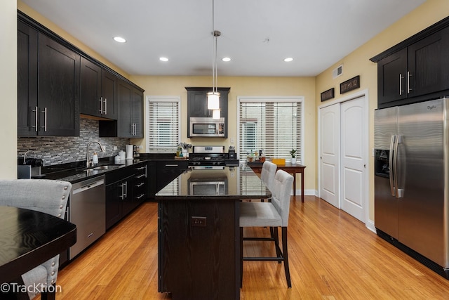 kitchen with decorative backsplash, a kitchen bar, a sink, dark stone counters, and stainless steel appliances