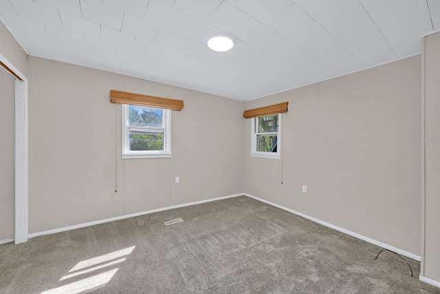carpeted spare room with visible vents and baseboards