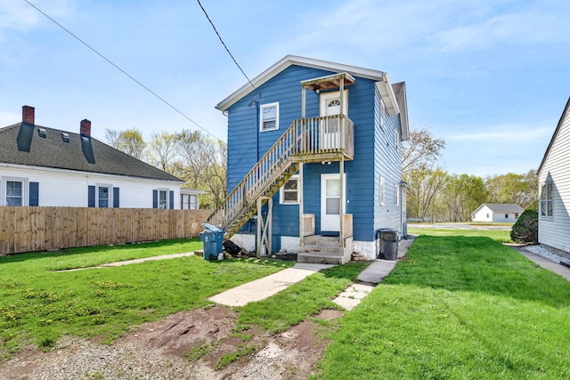 rear view of house featuring a lawn and fence