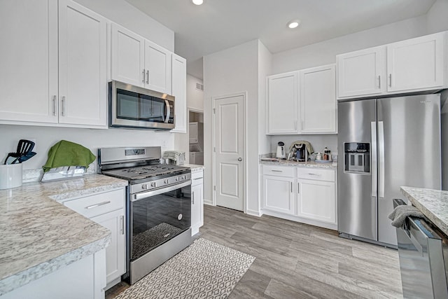 kitchen with recessed lighting, light wood finished floors, white cabinets, and stainless steel appliances