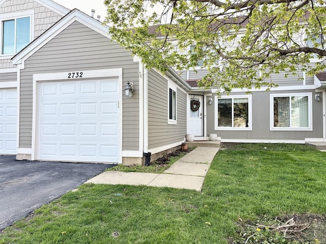 view of front of house featuring aphalt driveway, a front yard, and a garage