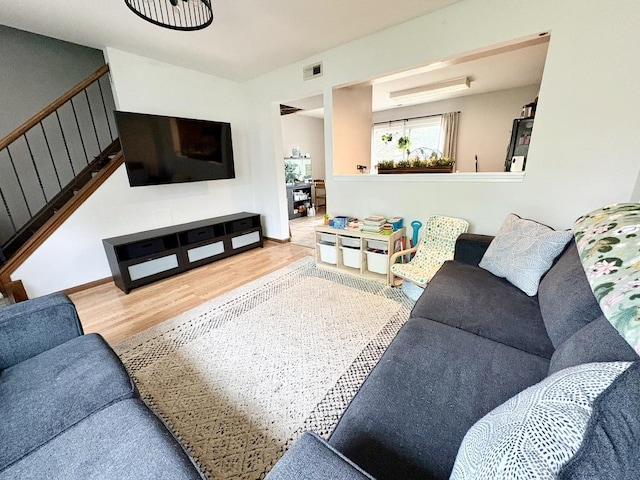 living area with visible vents, wood finished floors, and stairway