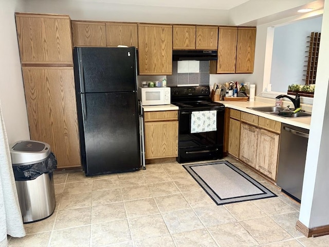 kitchen with brown cabinets, a sink, light countertops, black appliances, and under cabinet range hood