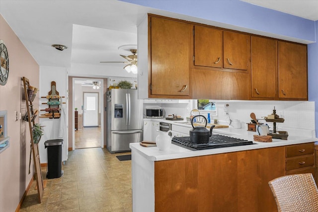 kitchen featuring ceiling fan, stainless steel appliances, a healthy amount of sunlight, and brown cabinets