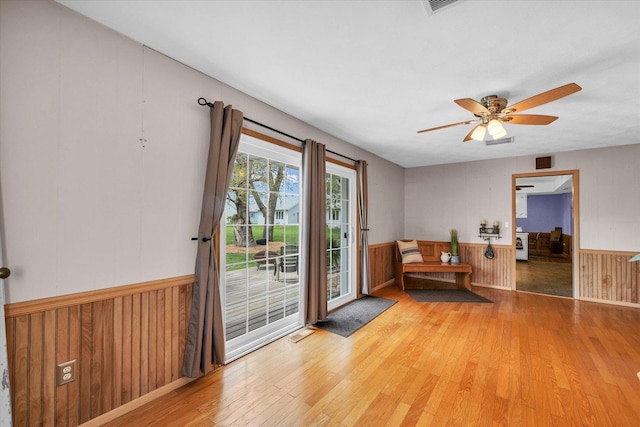 entryway with a wainscoted wall, visible vents, wood finished floors, and ceiling fan