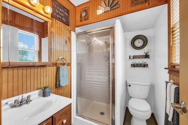 bathroom featuring a stall shower, vanity, toilet, and wood walls