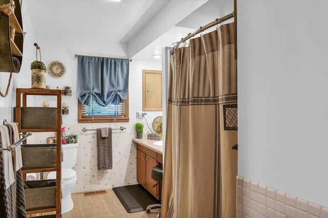 full bathroom featuring tile walls, toilet, wainscoting, visible vents, and vanity