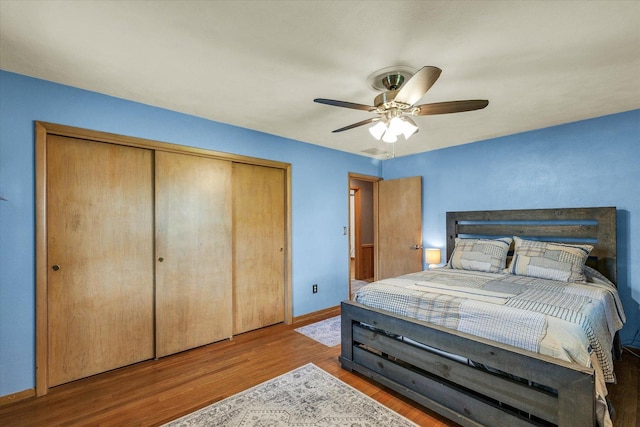bedroom featuring a closet, wood finished floors, baseboards, and ceiling fan