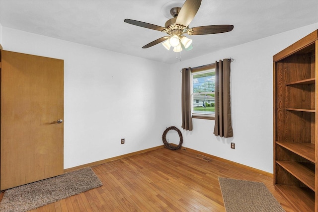 spare room featuring a ceiling fan, light wood-style floors, visible vents, and baseboards