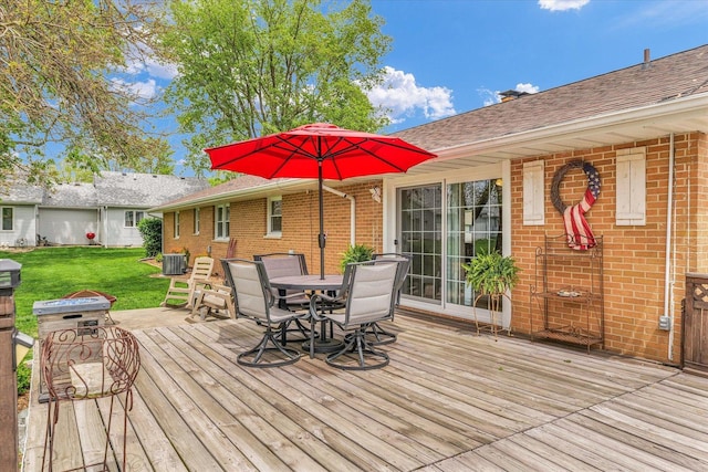 deck with central AC unit, outdoor dining area, and a lawn