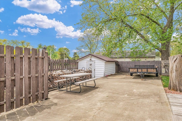view of patio / terrace with an outdoor structure, a fenced backyard, outdoor dining space, and a storage unit
