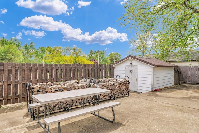 view of patio featuring a storage shed, an outdoor structure, outdoor dining area, and a fenced backyard