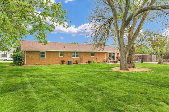 rear view of property featuring a yard, brick siding, fence, and a patio area
