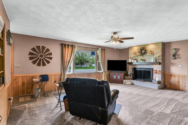 living area with a textured ceiling, wooden walls, carpet flooring, and a wainscoted wall