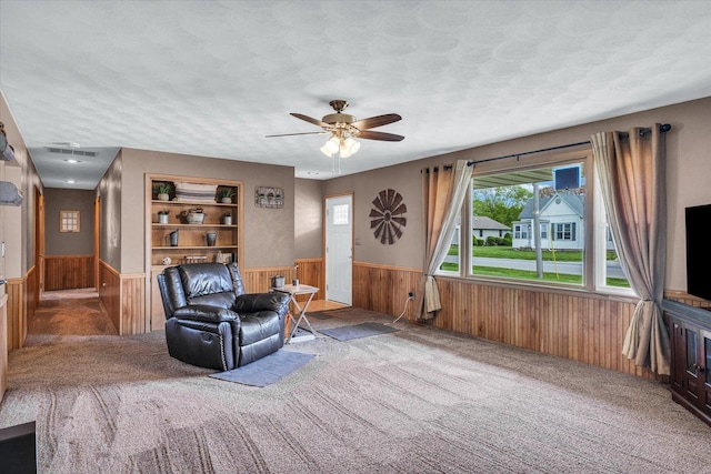 sitting room featuring carpet floors, wood walls, a wainscoted wall, and a wealth of natural light