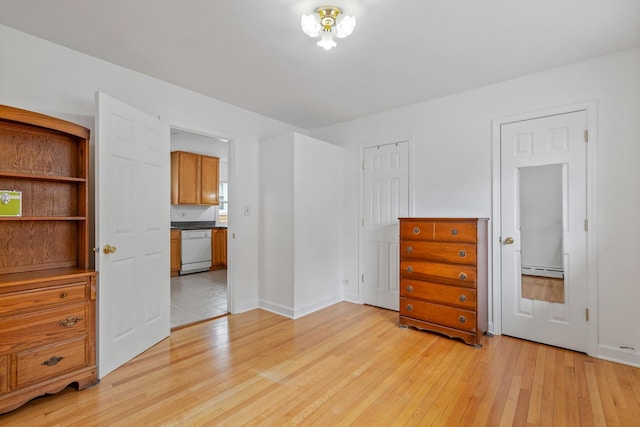unfurnished bedroom featuring light wood-style floors, baseboards, and a baseboard radiator