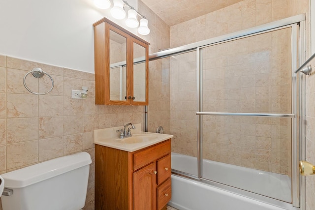 full bath with toilet, tile walls, bath / shower combo with glass door, and vanity
