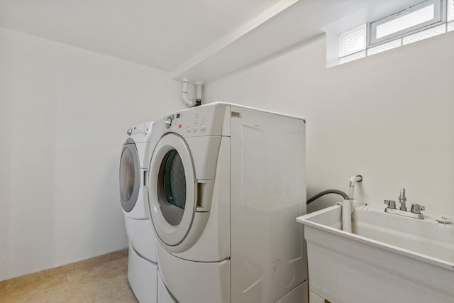 washroom with a sink, separate washer and dryer, light tile patterned floors, and laundry area