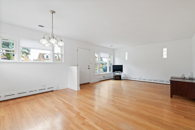 unfurnished living room featuring light wood-type flooring, a baseboard heating unit, visible vents, and an inviting chandelier