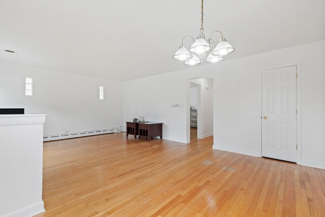 interior space featuring arched walkways, light wood-style flooring, a baseboard heating unit, and a notable chandelier