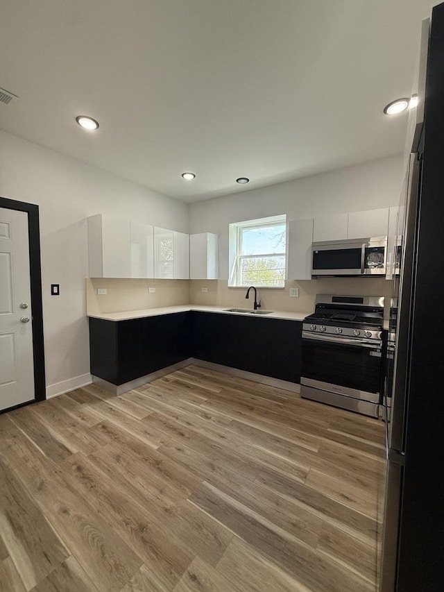 kitchen featuring light countertops, stainless steel appliances, dark cabinets, and a sink
