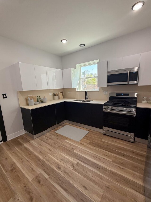 kitchen featuring white cabinetry, stainless steel appliances, light wood-style floors, and light countertops