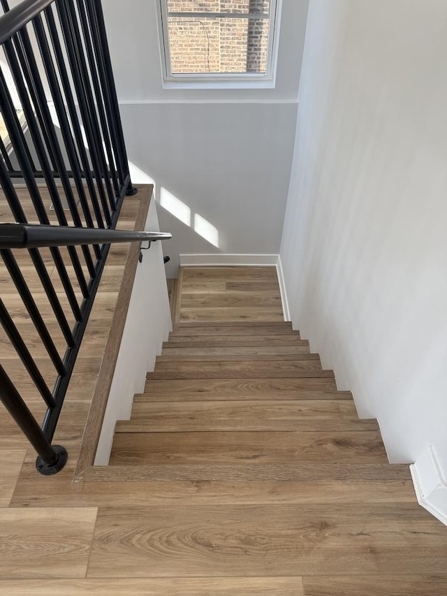 staircase featuring wood finished floors and baseboards