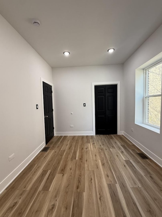 empty room with wood finished floors, recessed lighting, visible vents, and baseboards