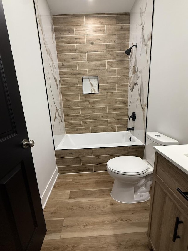 full bathroom featuring toilet, wood finished floors, vanity, and tiled shower / bath