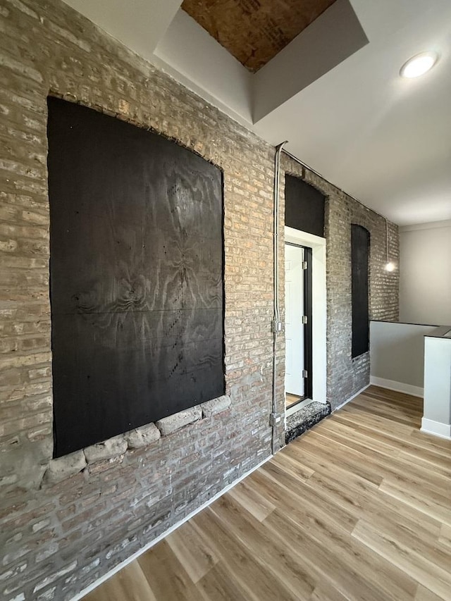 empty room featuring wood finished floors and brick wall