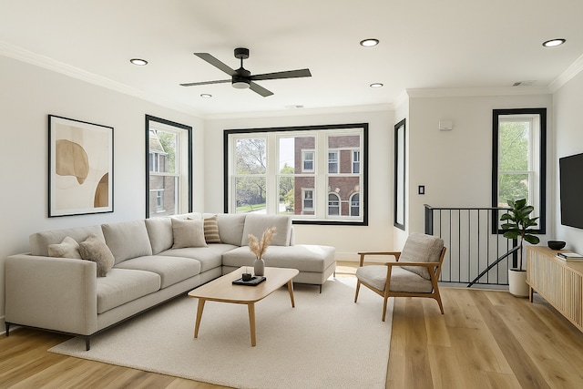 living area with crown molding, light wood finished floors, ceiling fan, and a wealth of natural light